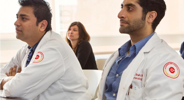 Medical residents and students attentively listening during a classroom lecture at Cooper University Health Care.