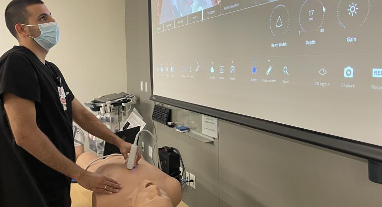 Medical resident performs ultrasound in simulation lab on mannequin.