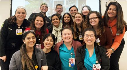 Group of Cooper University Health Care medical residents and staff smiling together in a classroom setting.