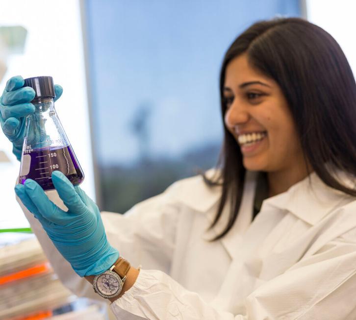 female researcher holding flask with purple liquid